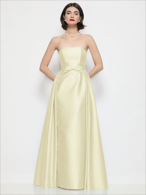 Champagne strapless satin column dress with bow waist and draped overskirt